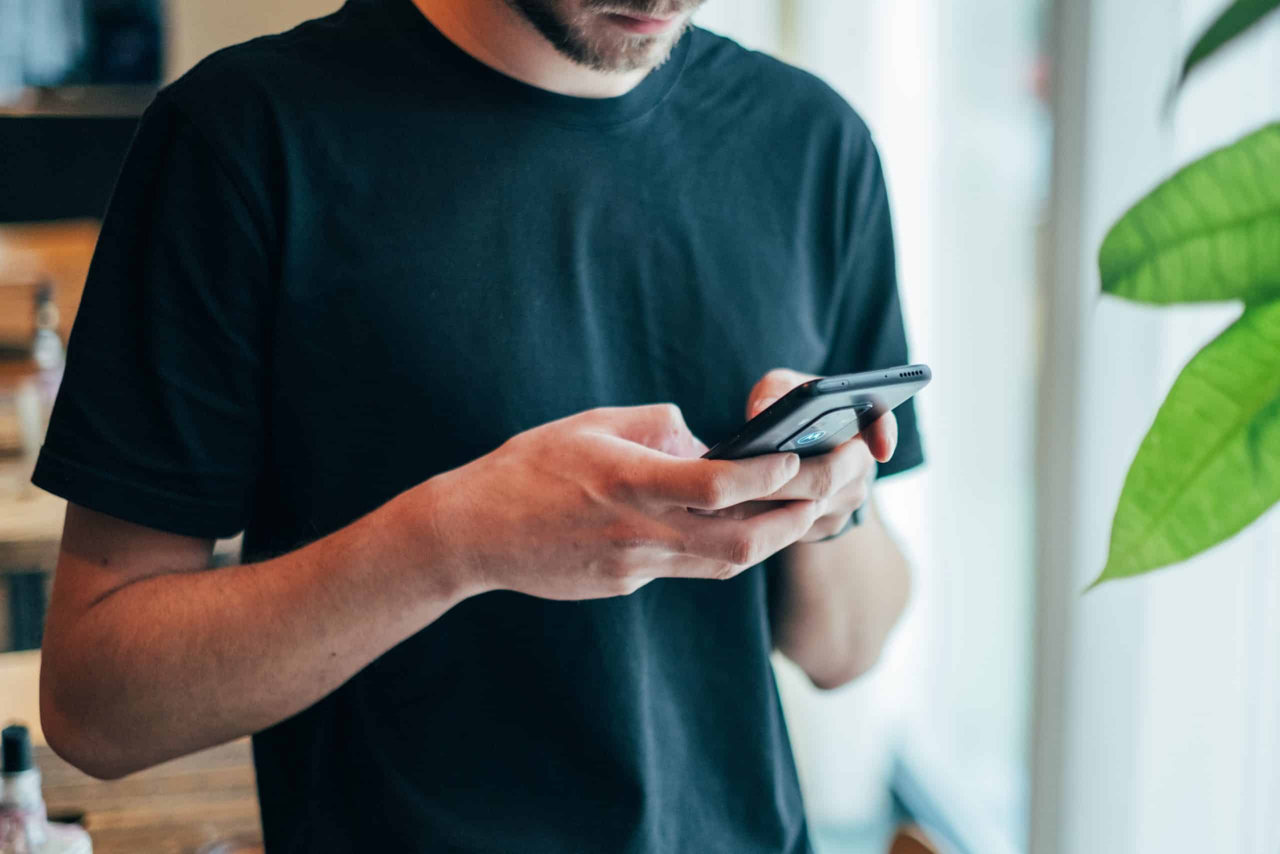 Man looking down and texting using his mobile device. His face is not shown.